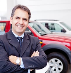 Business man working at a car dealer smiling